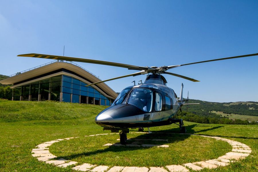 Moderner Helikopter auf einem Landeplatz vor einem Glasbau
