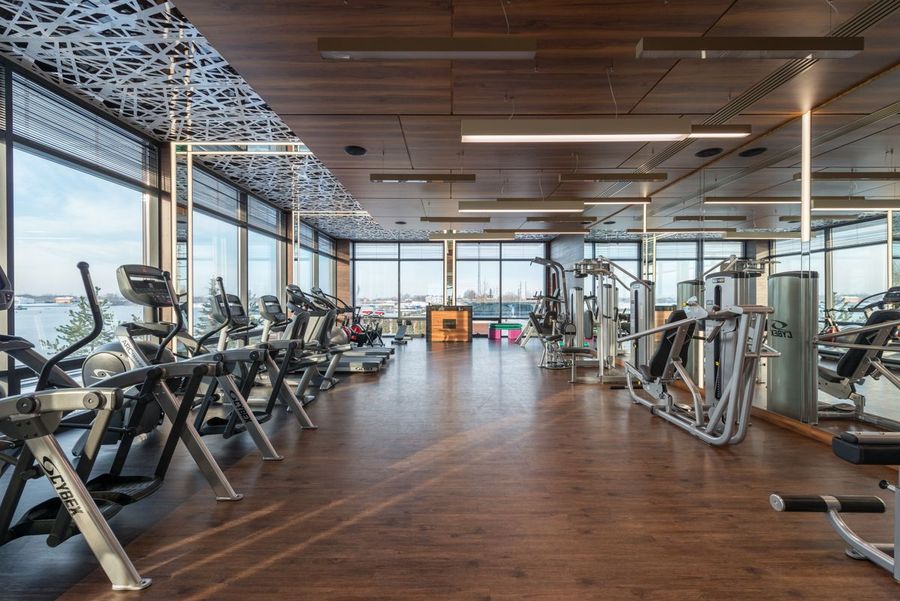 Laufbänder und Geräte in einem hellen Fitnessraum mit Panoramafenstern